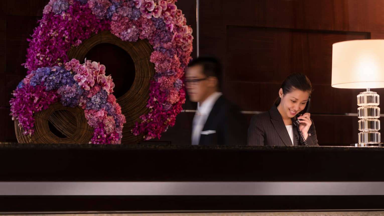 Staff at concierge desk in front of pink-and-purple floral wreaths