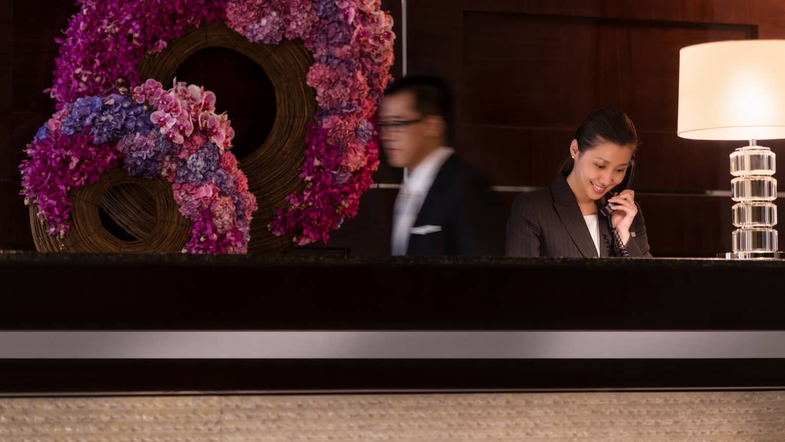 Staff at concierge desk in front of pink-and-purple floral wreaths
