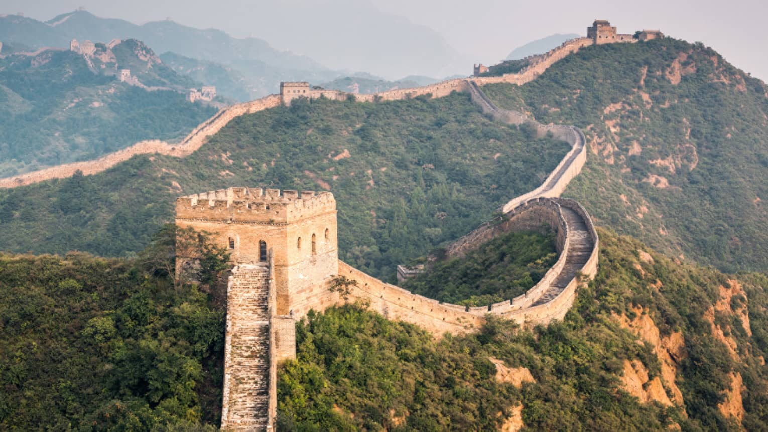 Great Wall of China winding along green mountain
