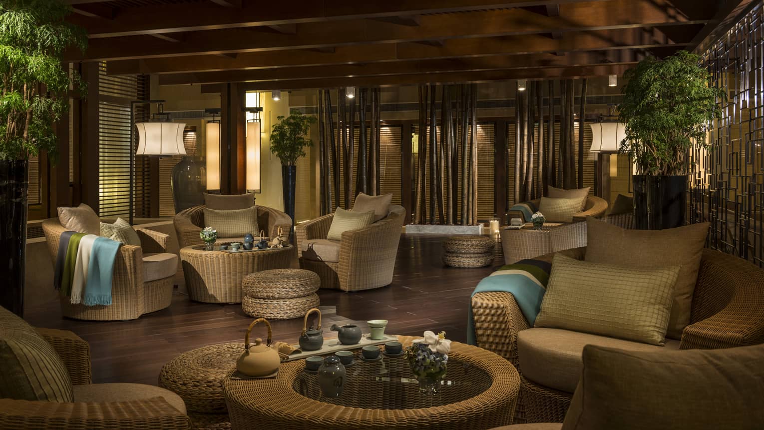 Dimly-lit Tea Garden lounge with light wicker furniture, tea service on tables