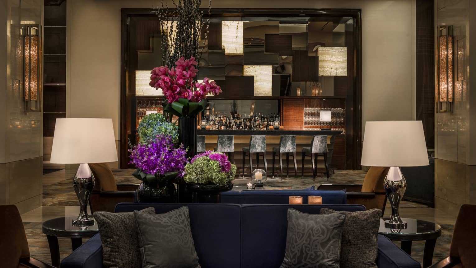 Opus Bar with grey stools behind lounge sofas, purple flowers