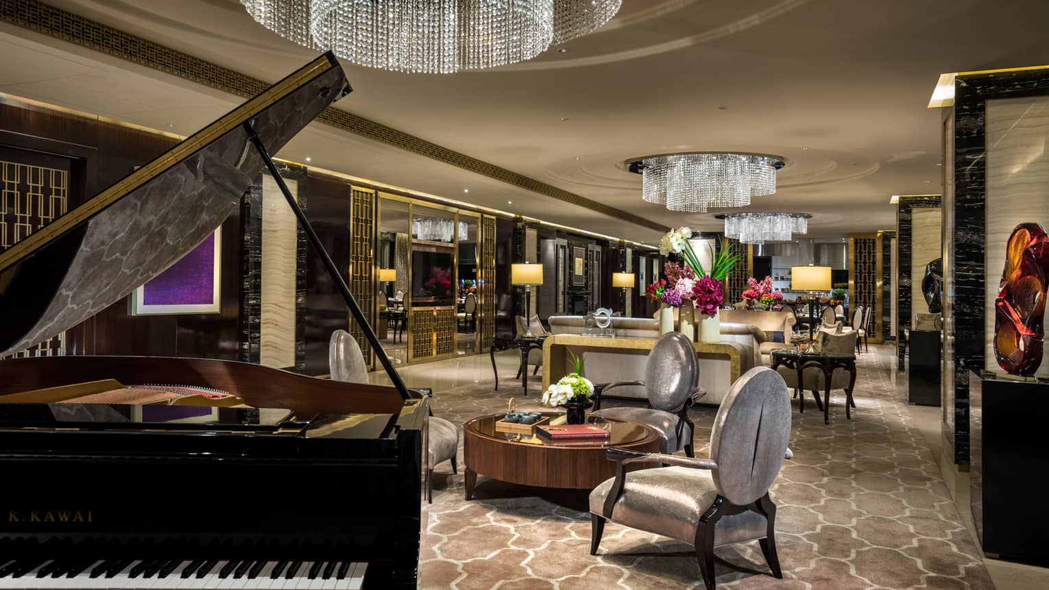 Side of grand piano in elegant lobby seating area under crystal chandelier 