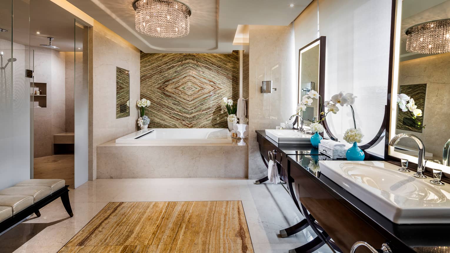 Large bathroom with square marble tub, decorative marble wall, wood vanity with double sinks