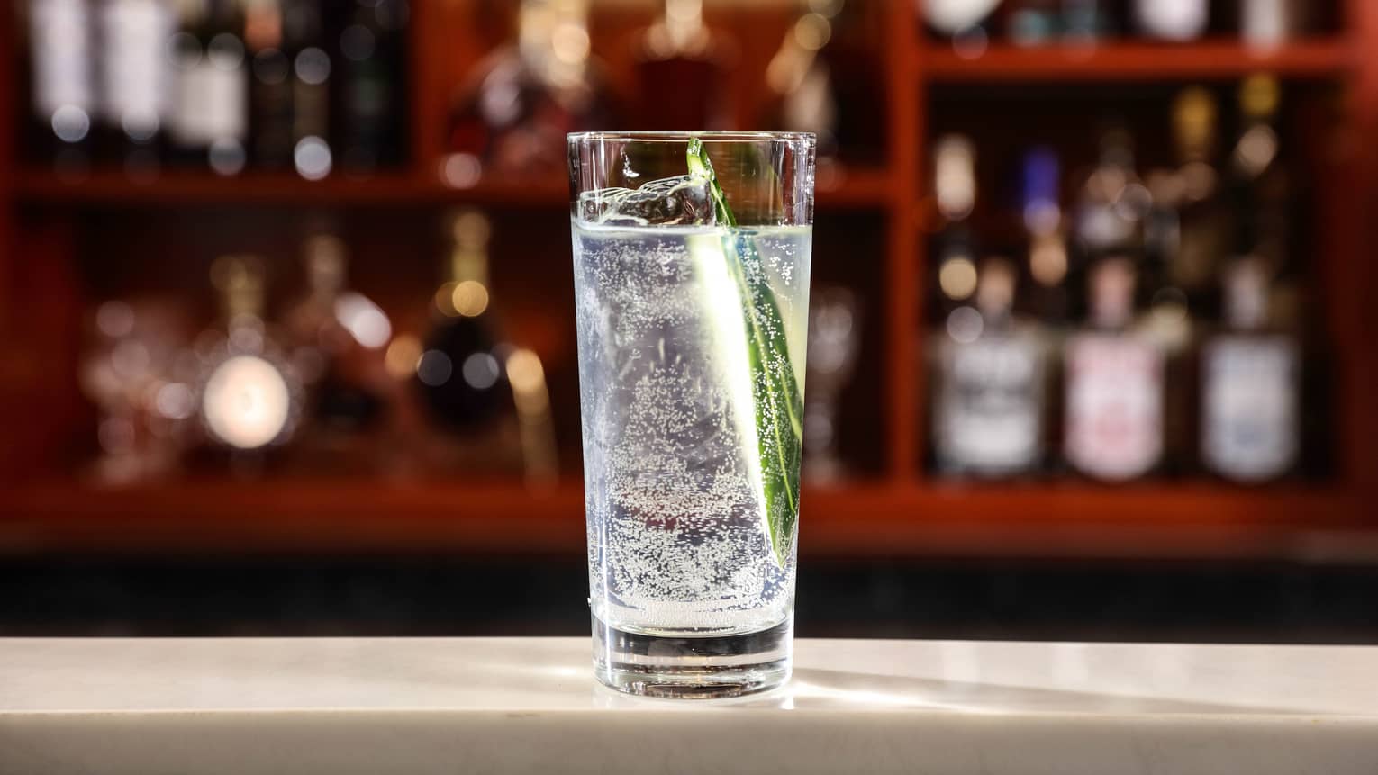 Tall glass with gin and tonic on bar 
