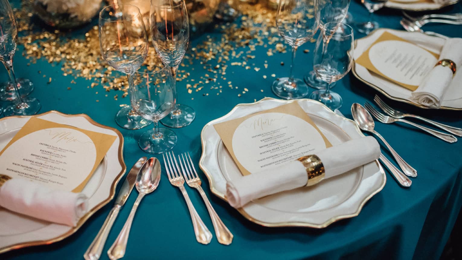 Elegant wedding banquet dining table, place settings with menus and gold accents