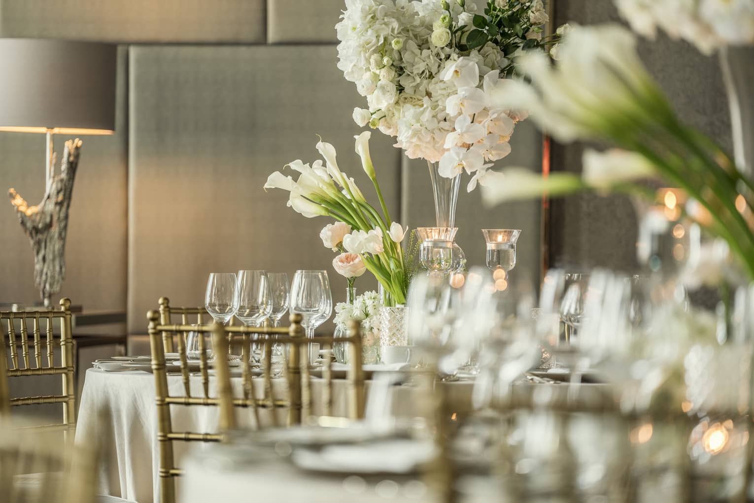 Close-up of empty wine glasses, vases with tall white flowers in Western Banquet room